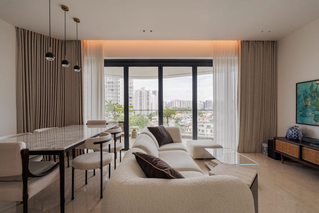 Modern organic living and dining room at The Amber Sanctuary featuring a curved bouclé sofa, a marble dining table, and a balcony with city views.